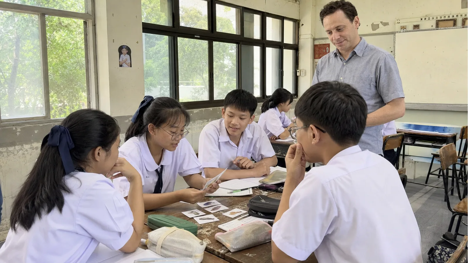 Thai students doing friendly group work while a foreign teacher observes supportively